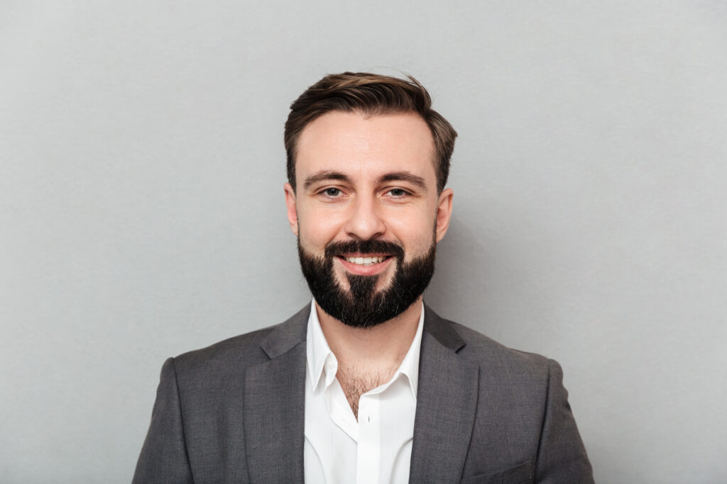 close up portrait of young bearded man in white shirt and jacket